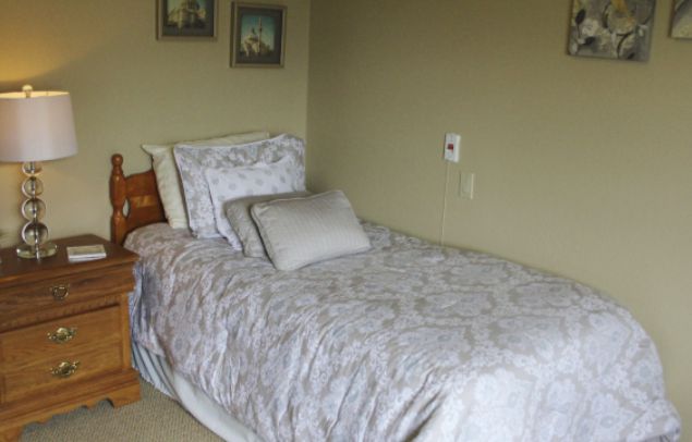 A cozy single bed with patterned bedding and a pillow in a neatly decorated bedroom.