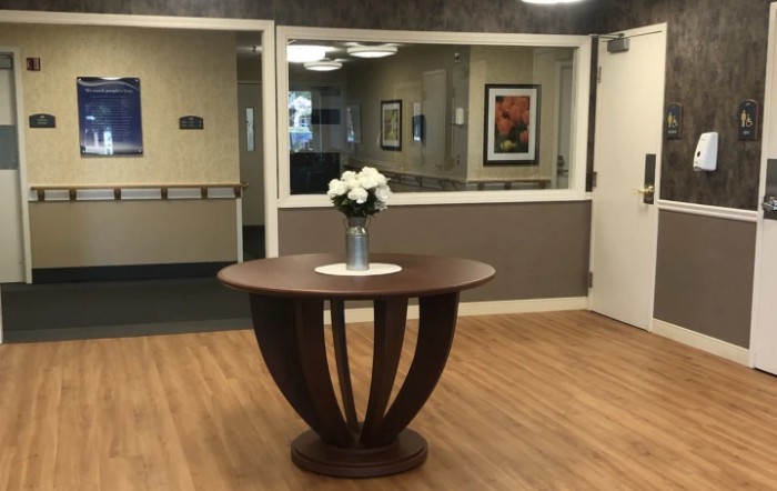 A wooden table with a vase of flowers in a lobby area.