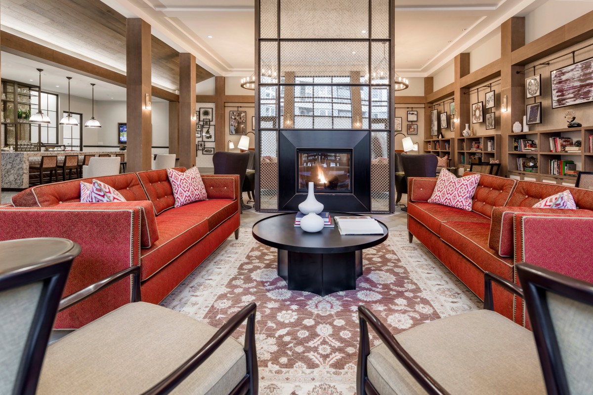 Elegant living room with red sofas and a central fireplace.