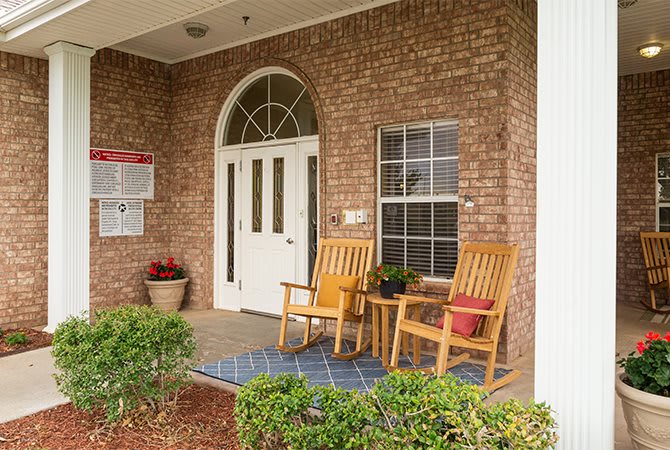 A cozy porch with two wooden chairs and potted plants.