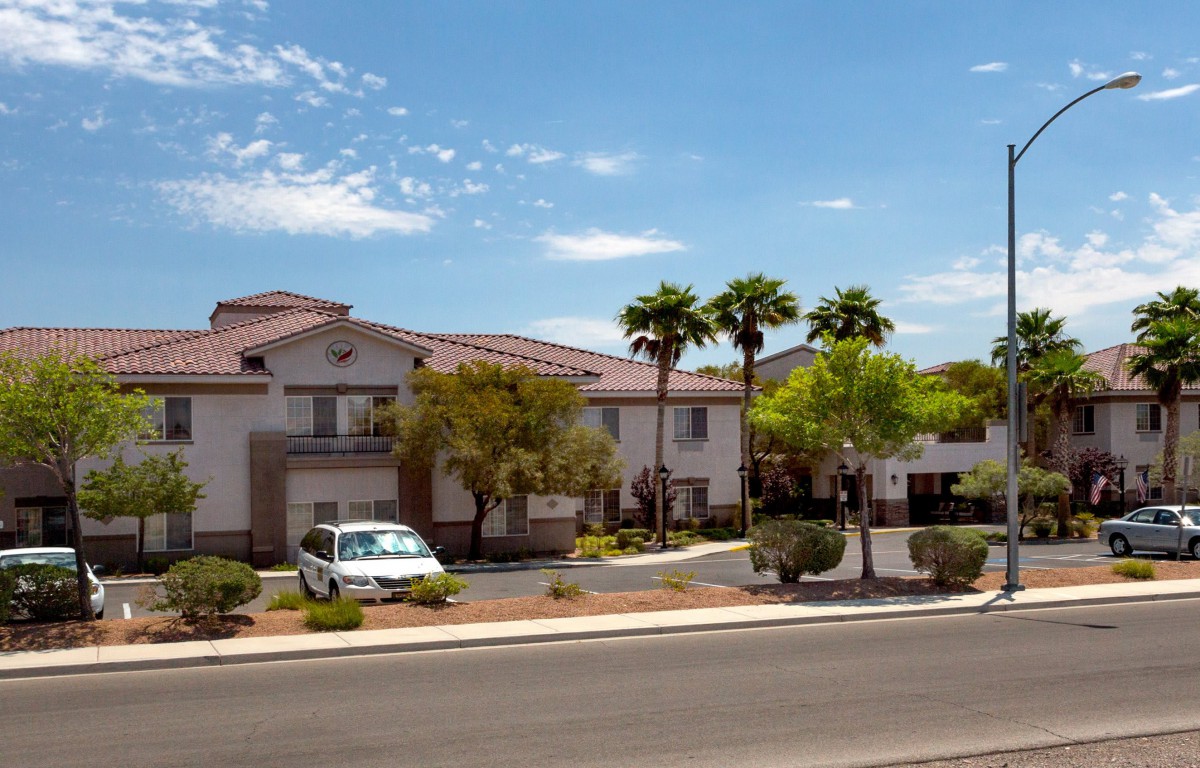 A suburban residential building with palm trees on a sunny day.