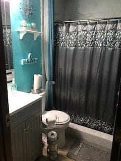 A neatly arranged bathroom with a teal wall, featuring a vanity, toilet, and patterned shower curtain.