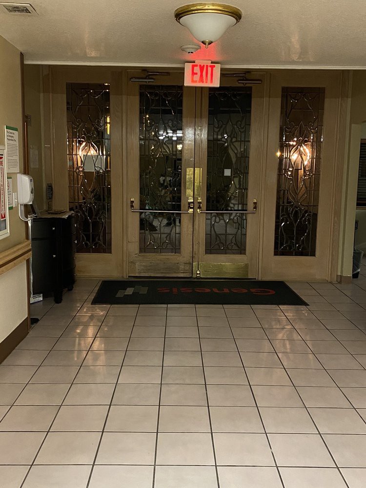 The image shows a tiled lobby entrance with double glass doors and an exit sign above.