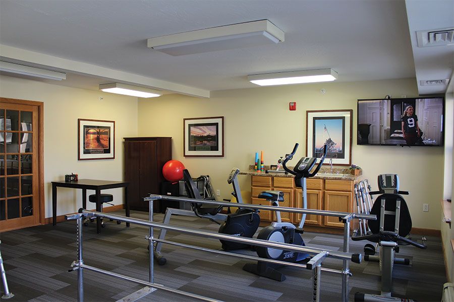 A rehabilitation room equipped with exercise machines and parallel bars.