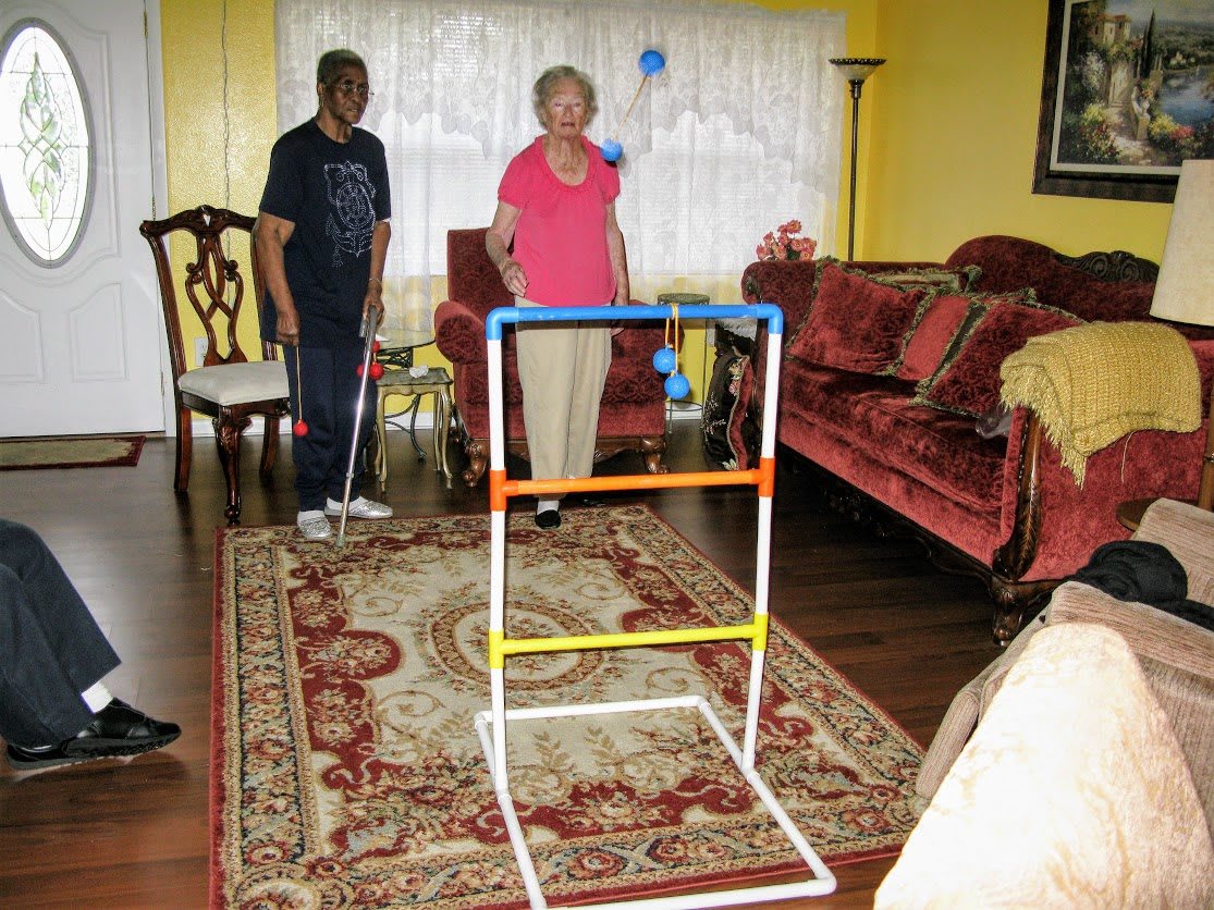 Two people playing a game of ladder toss in a living room.