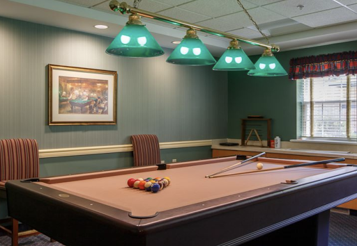 A cozy game room featuring a well-lit pool table and green lamps.