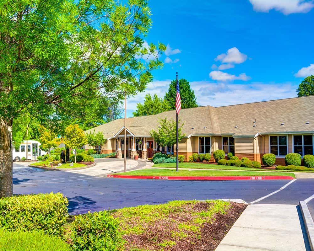 A sunny day outside a single-story office building with surrounding greenery and a well-maintained parking area.