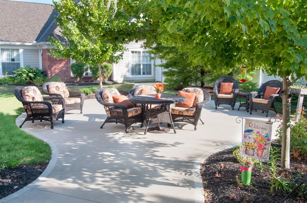 A sunny outdoor patio area with comfortable furniture set amidst greenery.