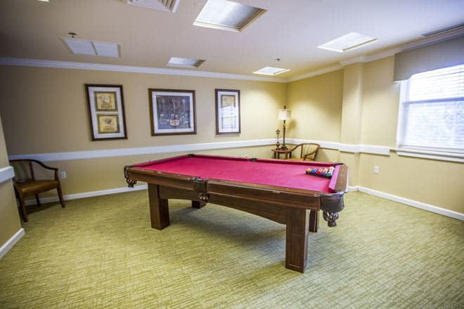 A cozy game room featuring a red-felt pool table and framed artwork on the walls.