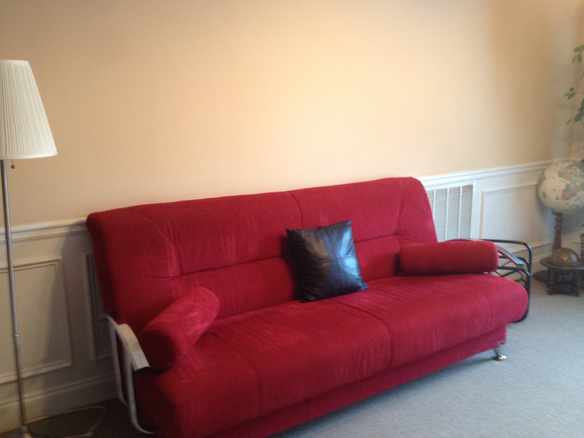 A minimalist living room featuring a vibrant red sofa with decorative cushions.