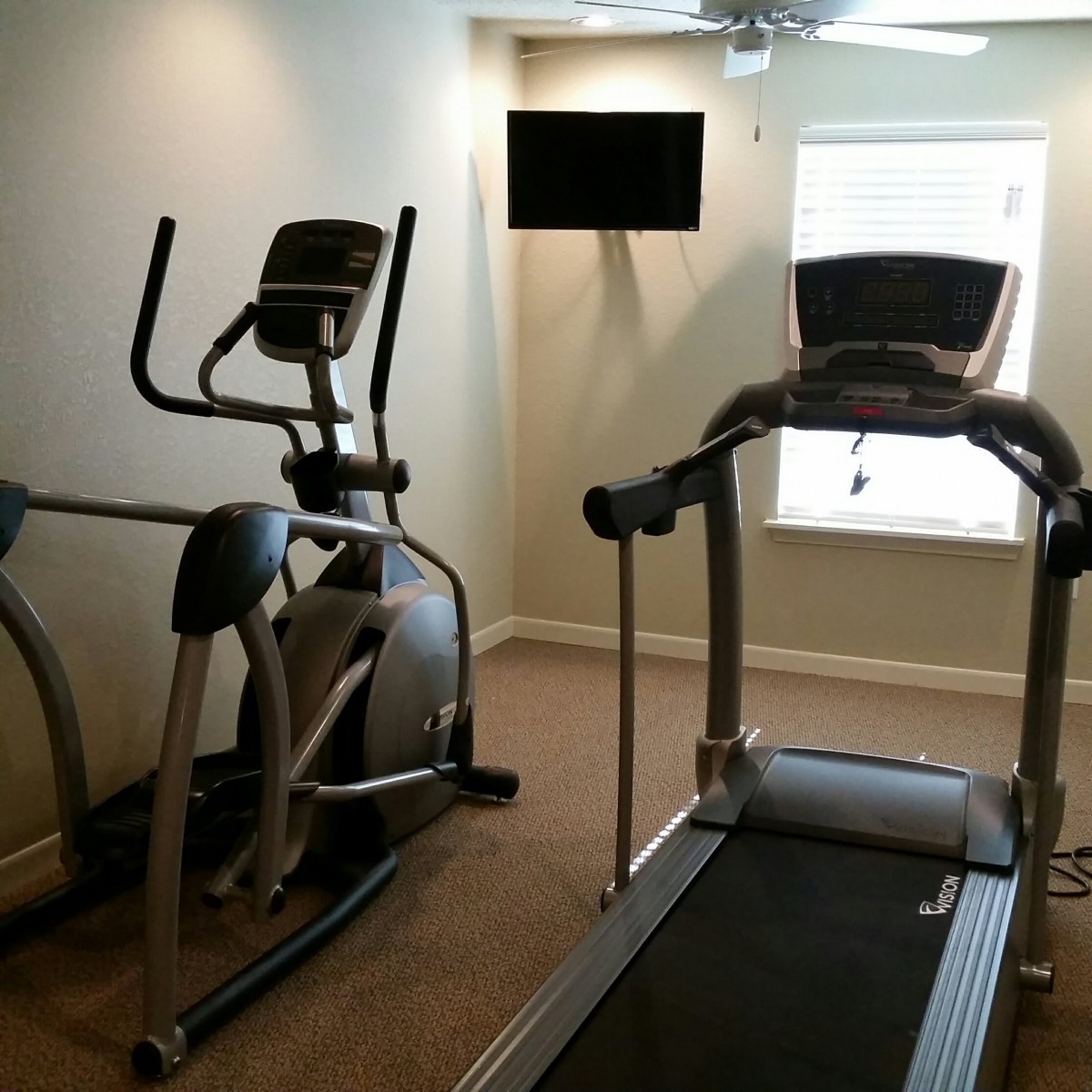 A small indoor gym with a treadmill and elliptical machine.