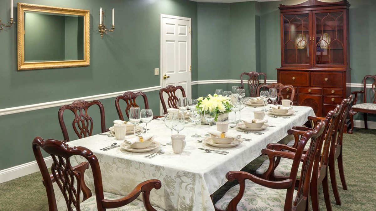 A formal dining room with a fully set table, featuring elegant china and silverware.