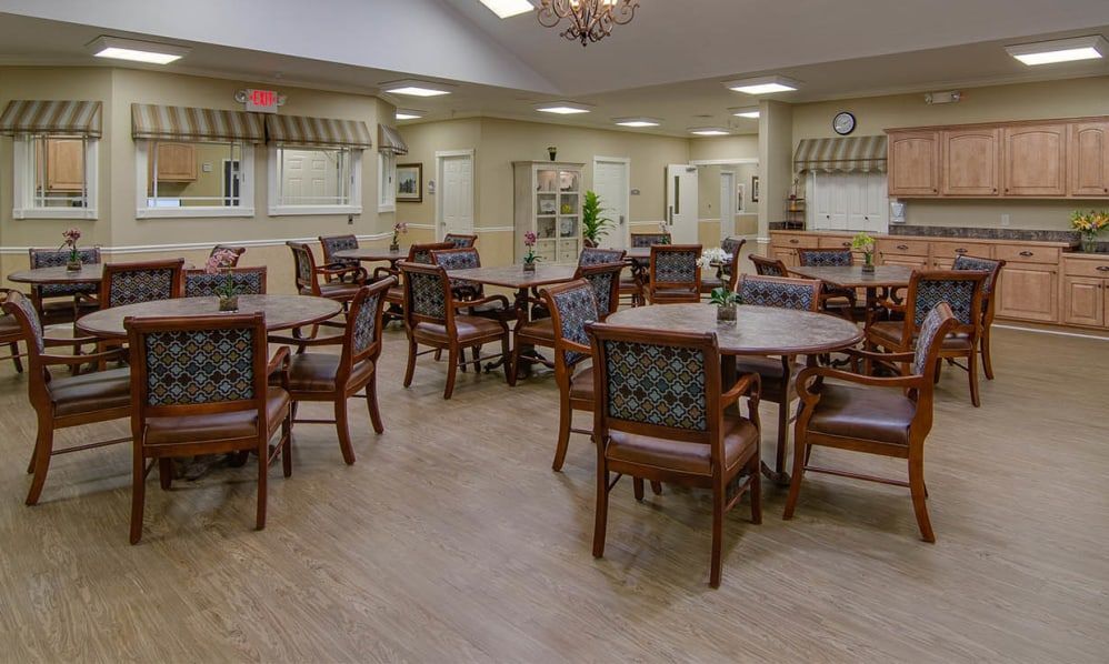 A spacious and well-lit dining area with multiple tables and chairs arranged neatly.