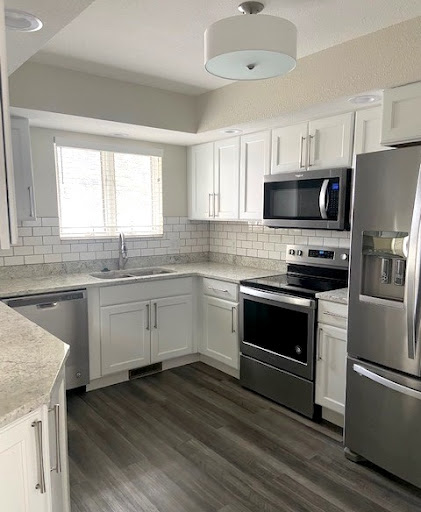 A newly renovated modern kitchen featuring white cabinets, stainless steel appliances, and ample natural light.