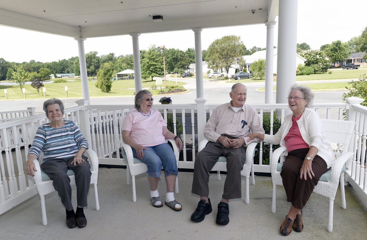 A group of seniors sitting and chatting on a porch.
