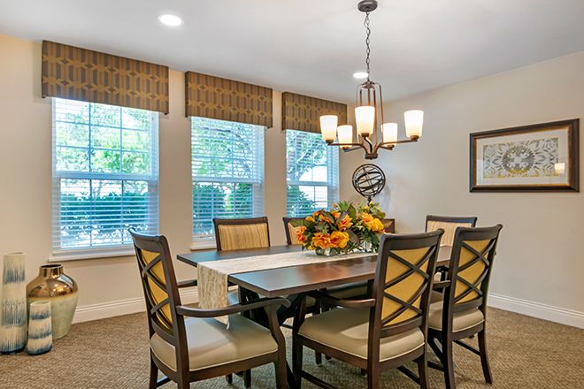 A well-decorated dining room with a chandelier and large windows.