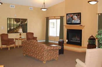 A cozy living room with a sofa, lamp, and a fireplace under a mounted television.