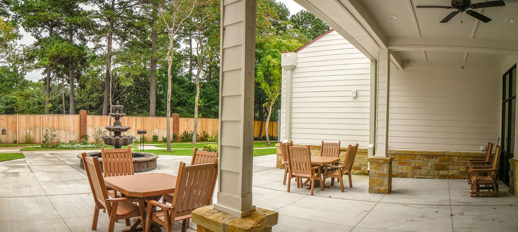 A peaceful patio area with wooden tables and chairs overlooking a garden.