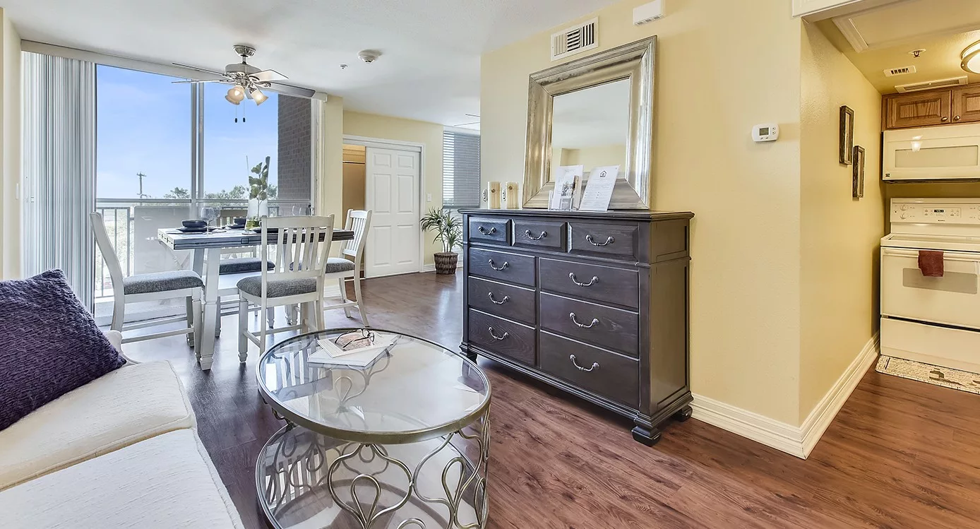 A modern living room with a large dresser, mirror, and a stylish coffee table on wooden flooring.