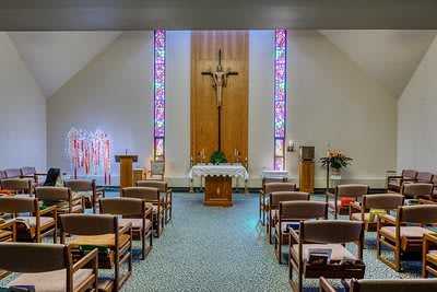 A serene chapel interior featuring a crucifix and stained glass windows.
