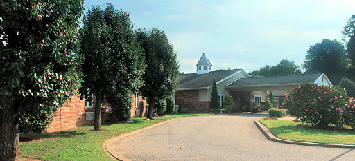 A peaceful scene featuring a building surrounded by trees and a winding road.