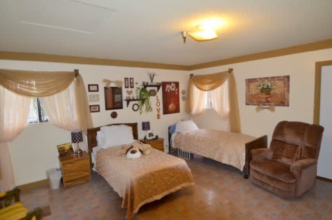 A cozy bedroom with two twin beds, decorated in warm brown tones and featuring traditional wall decor.