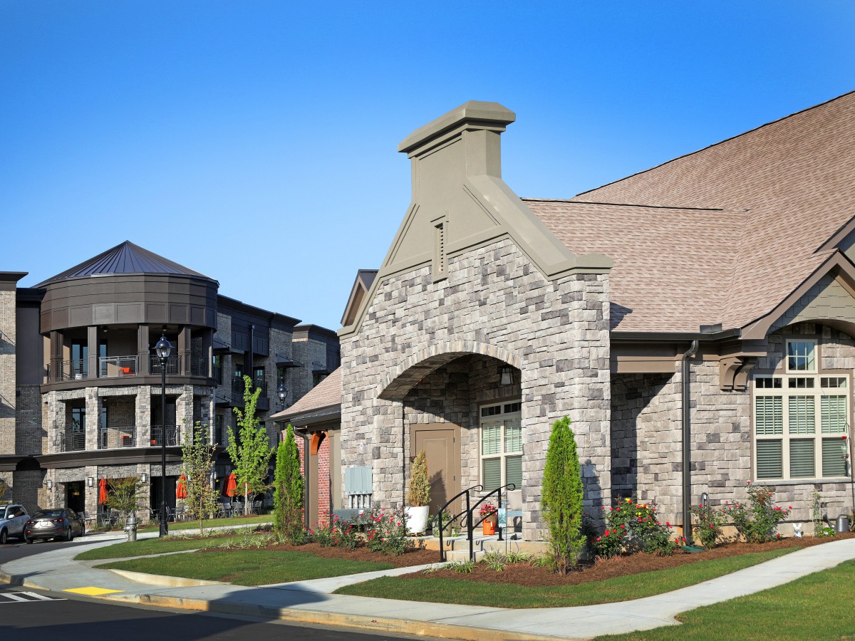 A modern residential building with a stone facade and well-maintained landscaping.