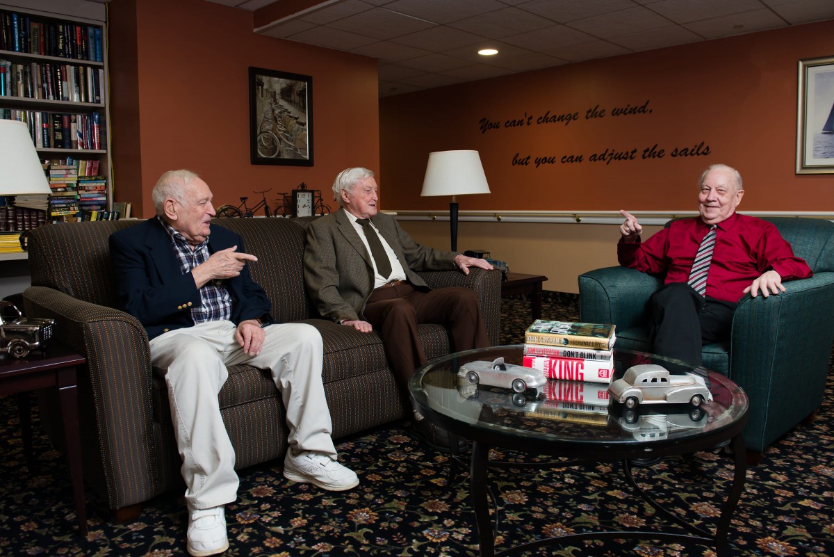 A group of elderly men sitting and conversing in a comfortable living room setting.