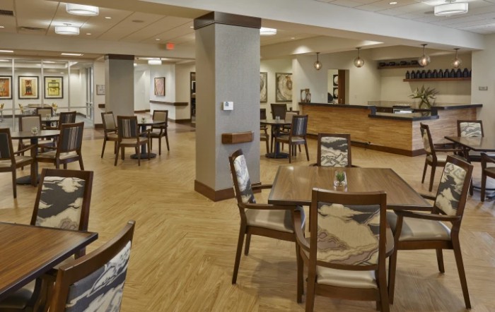 A spacious, modern dining area with wooden flooring and neatly arranged tables and chairs.
