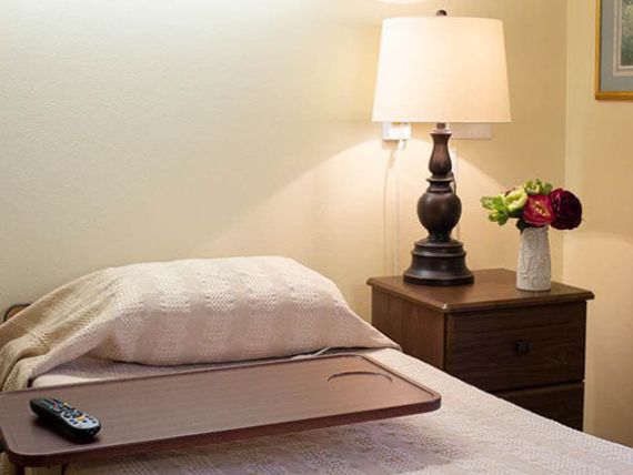 A cozy bedroom setup with a lamp and flower vase on the nightstand.