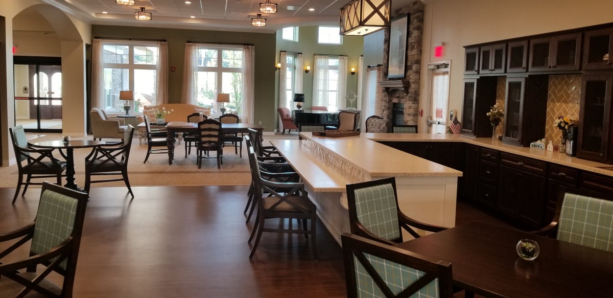 A spacious modern living area with a dining table, kitchen island, and large windows.