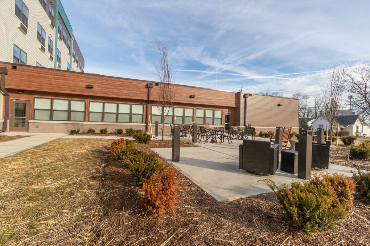 A modern building with an outdoor patio area and landscaped surroundings under a clear sky.