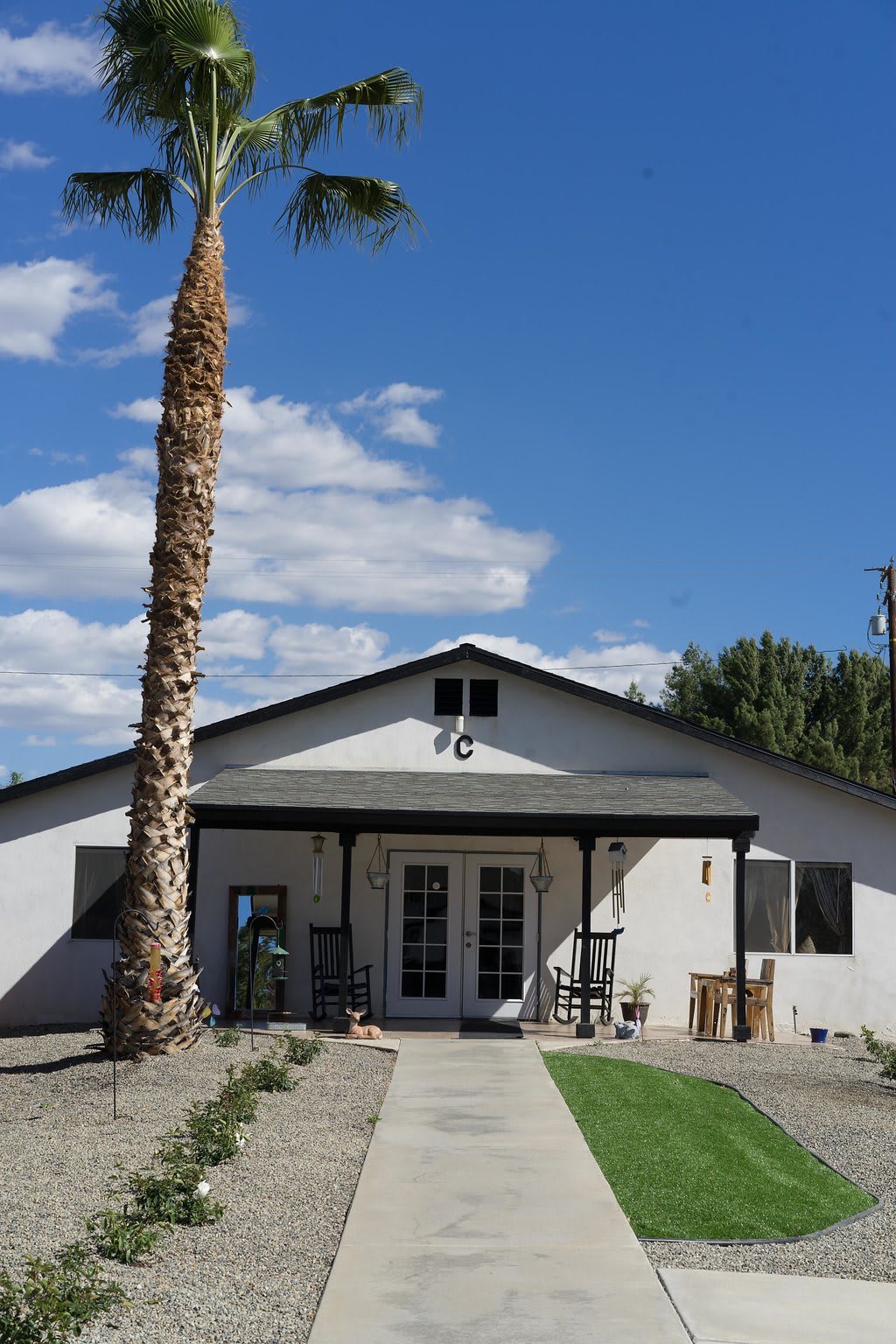 A single-story white house with a palm tree and a clear blue sky in the background.
