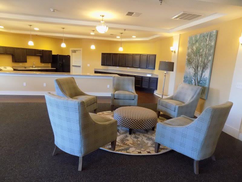 A modern lounge area with upholstered chairs and a round ottoman in the center.