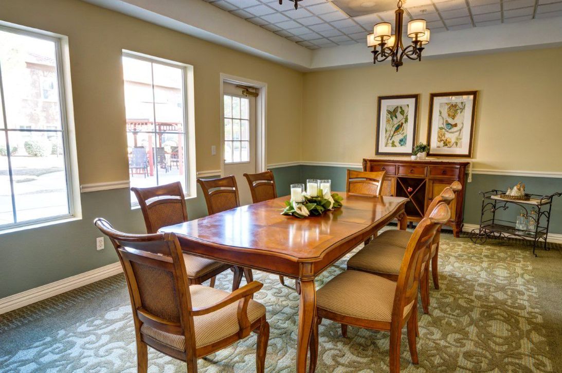 A well-furnished dining room with a wooden table, chairs, chandelier, and artwork.