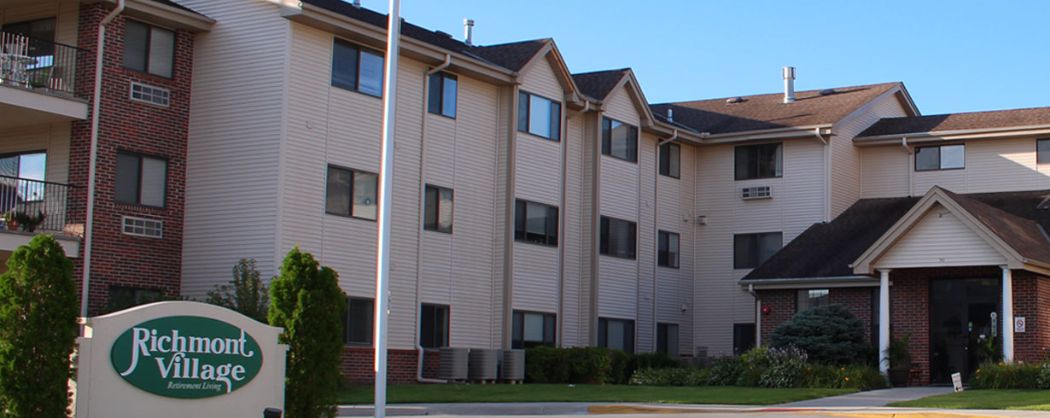An exterior view of a multi-story apartment building under a clear blue sky.