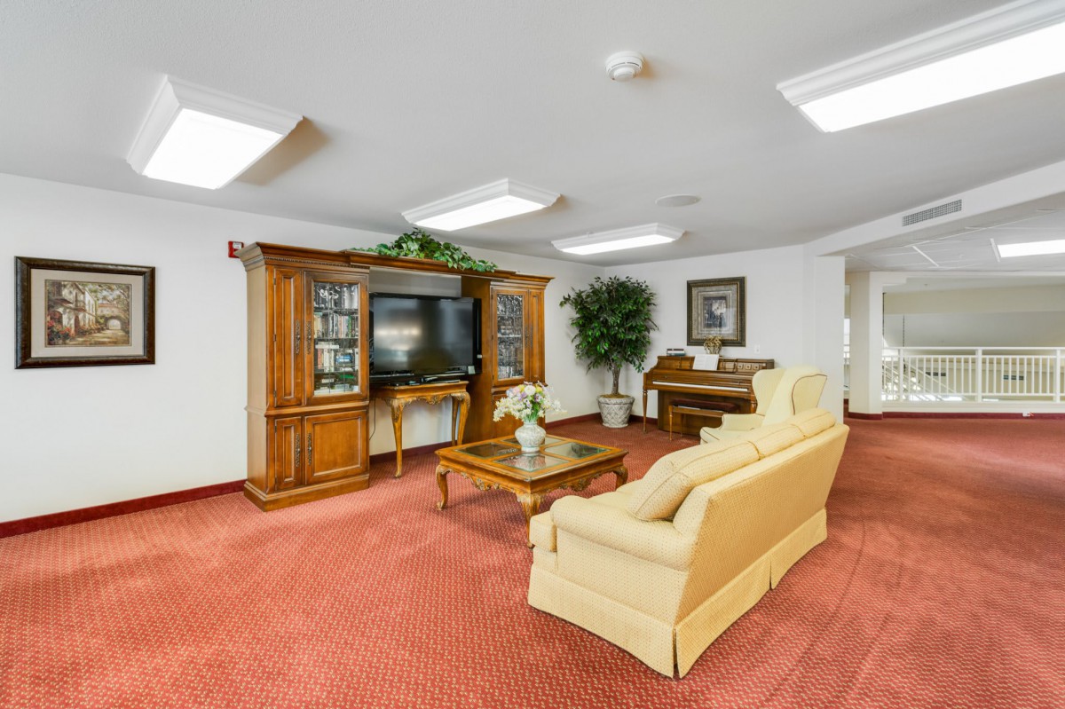 A cozy living room featuring a sofa, coffee table, entertainment center with a television, and a piano.