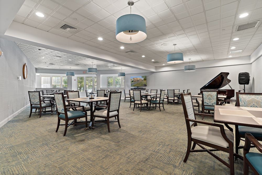 A spacious dining room with neatly arranged tables and chairs, featuring modern ceiling lights and large windows.
