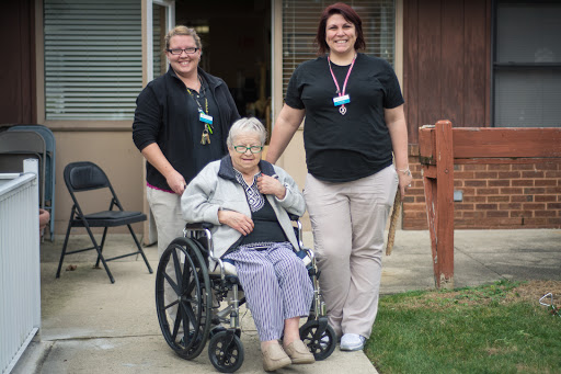 A moment of care and support, showcasing the bond between an elderly woman in a wheelchair and her dedicated caregivers.