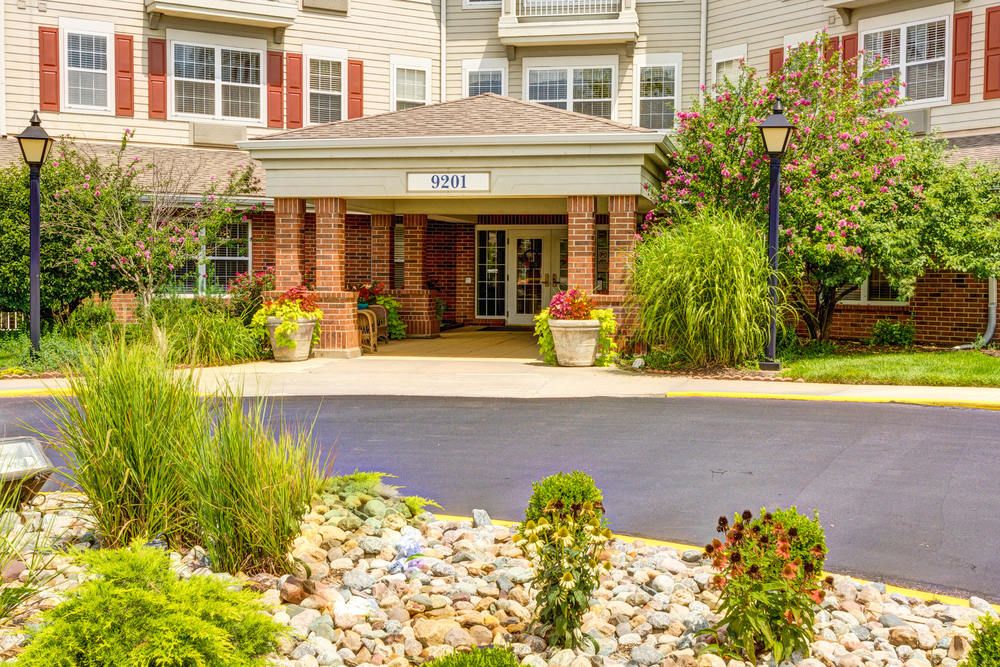 A well-landscaped building entrance with plants and a paved walkway.