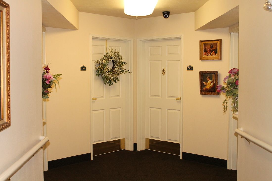 A hallway with two decorated doors, adorned with a wreath and artwork on the walls.