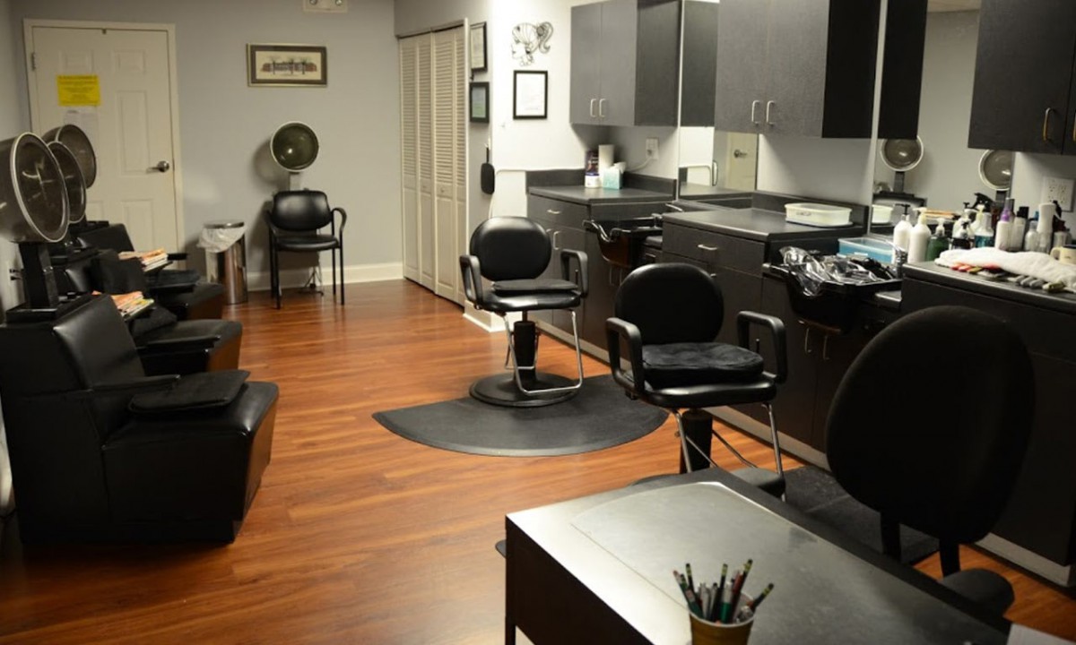 A modern hair salon interior with sleek black chairs and wooden flooring.
