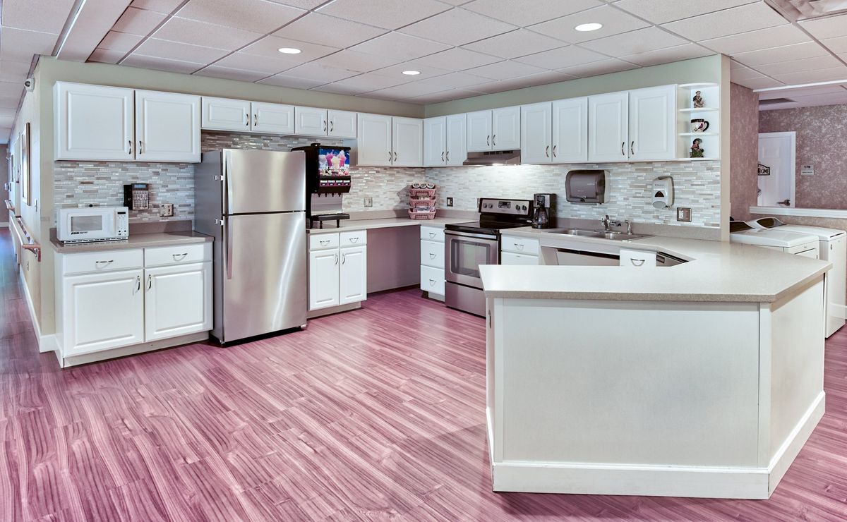 A modern kitchen with stainless steel appliances, white cabinets, and a hardwood floor.