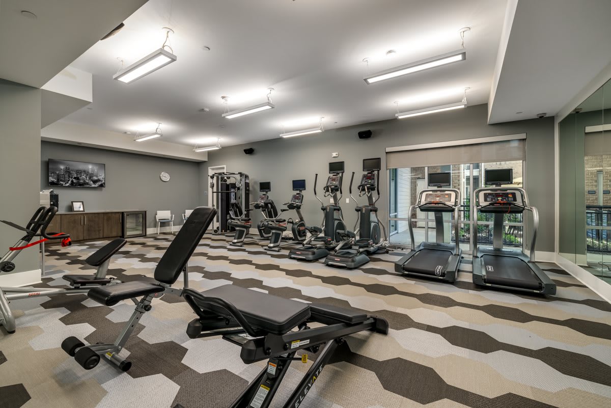 A modern gym with various exercise equipment including treadmills and weight benches.