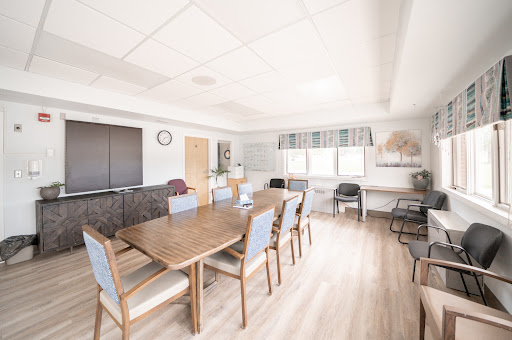 A spacious and well-lit meeting room featuring a large table surrounded by chairs, suitable for collaborative work.