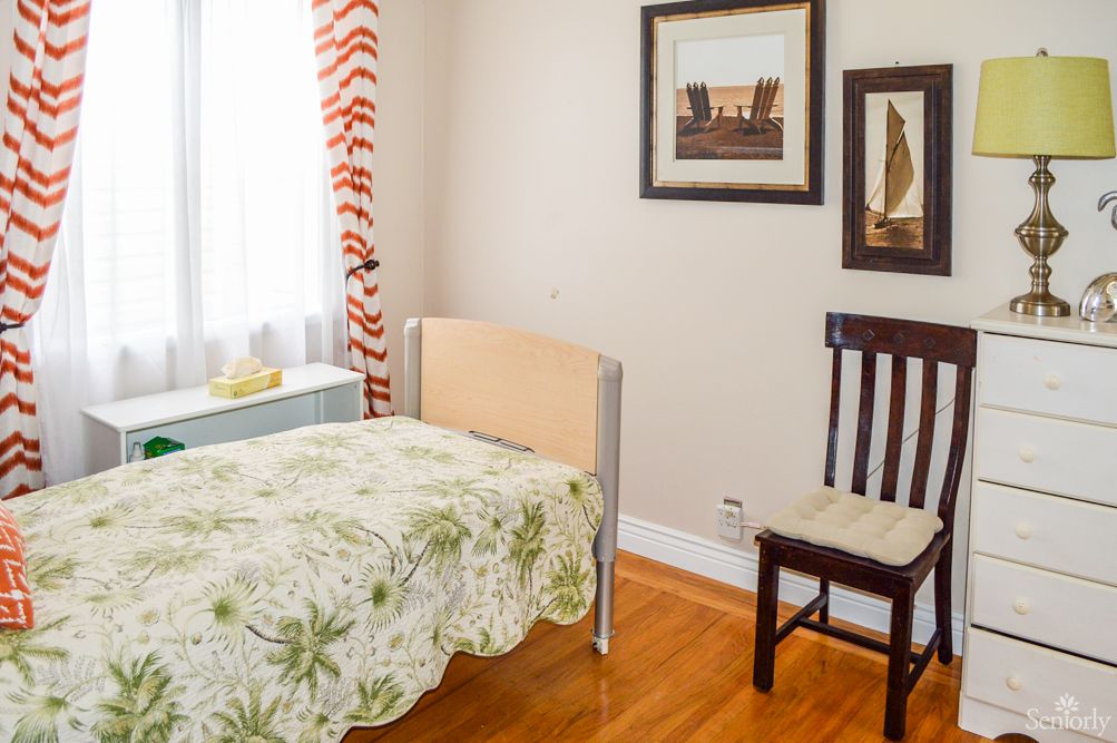 A cozy bedroom with a single bed, chair, and framed artwork on the wall.