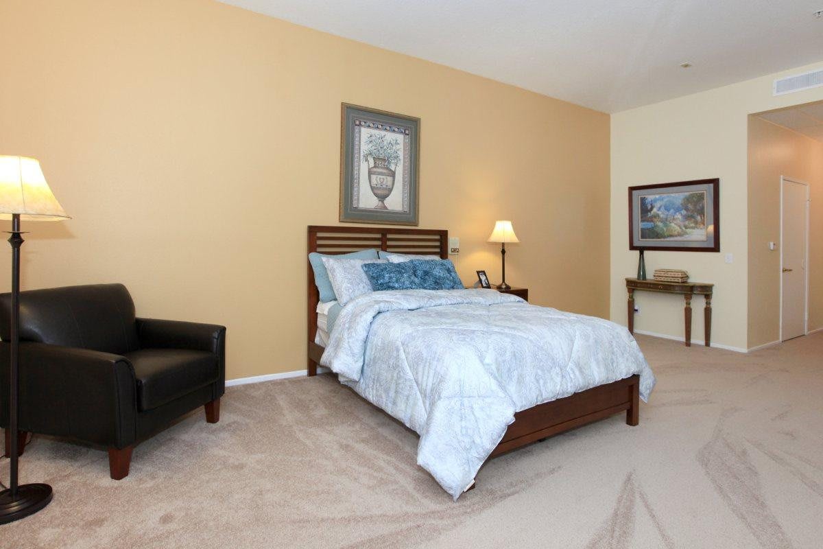 A well-decorated bedroom with a comfortable bed, artwork on the walls, and soft lighting.