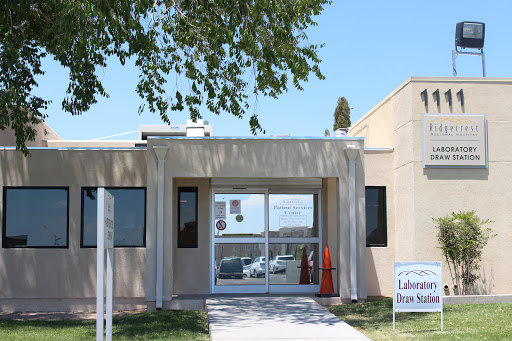 Entrance of a modern building with large windows and a sign in front.