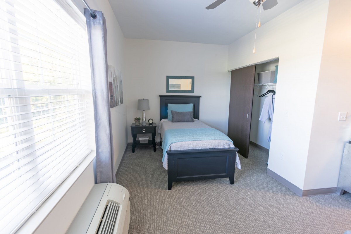 A minimalist bedroom with a single bed, nightstand, and closet.