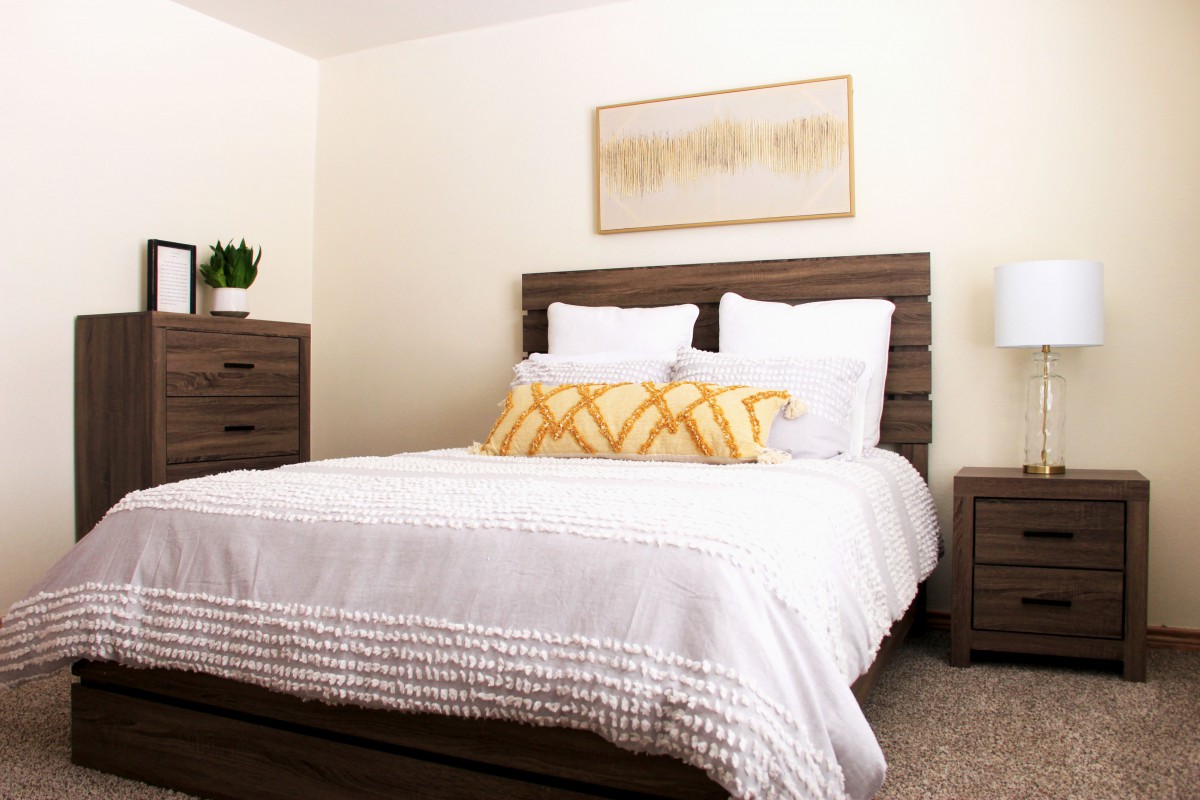 A cozy bedroom with a neatly made bed and stylish wooden furniture.